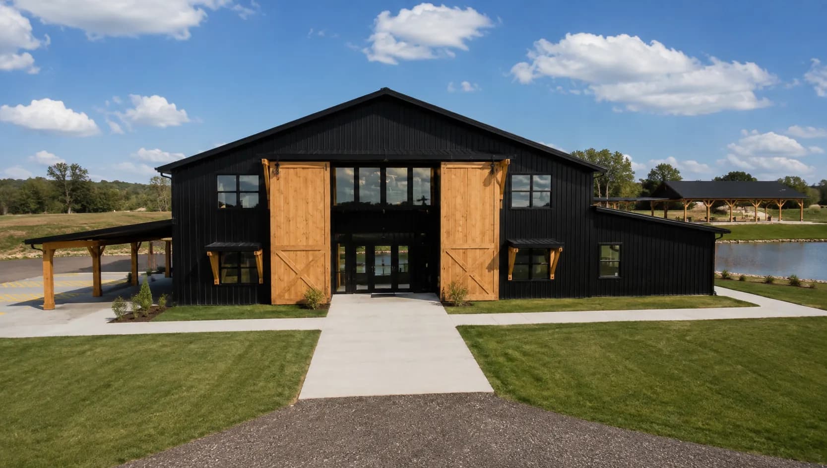 Architectural rendering of the front facade of Antelope Creek Ranch Venue near Wichita, Kansas, with cedar barn doors, covered porches on both wings and the pond visible to the right.